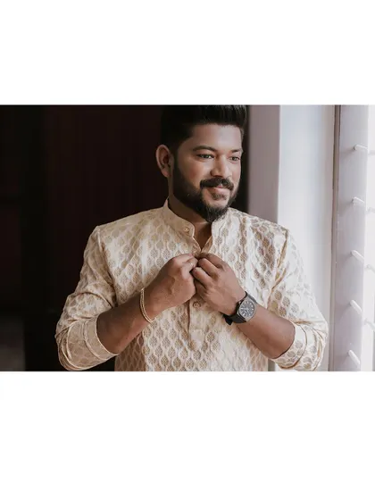 A portrait of the groom getting ready, adjusting his kurta.