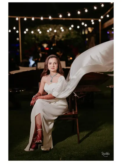 The bride's modern white gown featured a dramatic, flowing one-shoulder drape, creating a memorable silhouette for their intimate dinner party.