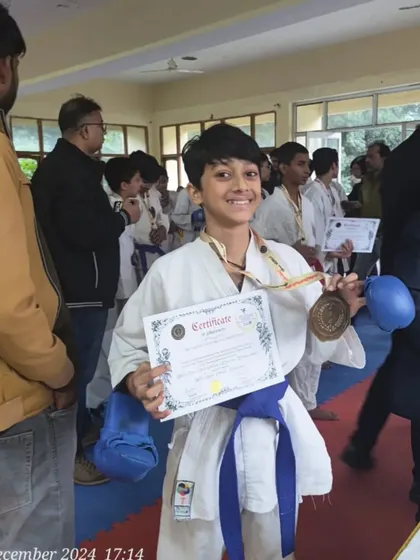 A happy champion with his medal and certificate. The smile says it all. This is the reward for months of disciplined training.