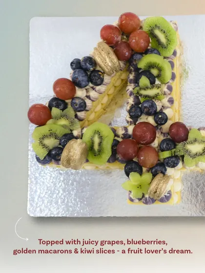 A closer look at the number "4" from the 40th birthday tart-cake. You can see the detail of the piped cream and the careful arrangement of juicy grapes, blueberries, and kiwi slices.