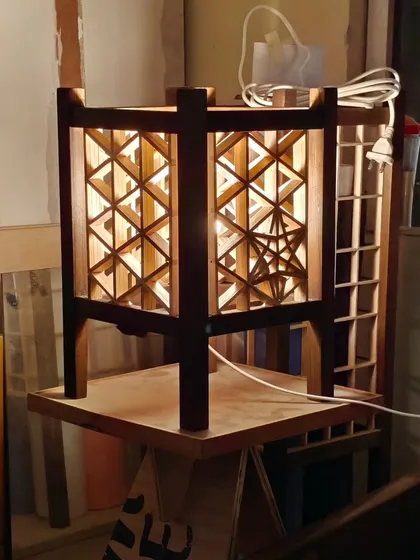 The same triangle grid Kumiko lamp, now powered on. The light transforms the piece, creating a warm and inviting ambiance and showcasing the complex joinery.