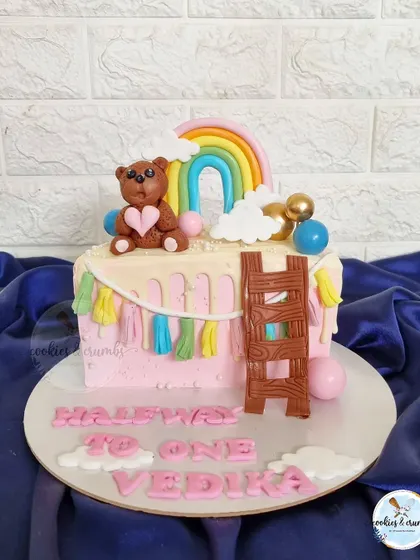 Another take on the "Halfway to One" theme, this half-cake features a cute teddy bear, a rainbow, and a colorful tassel garland made of fondant.
