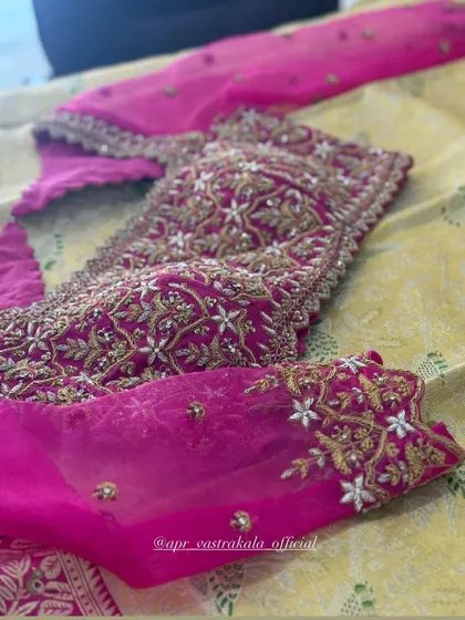 A close-up of the dense embroidery on the body of the pink blouse.