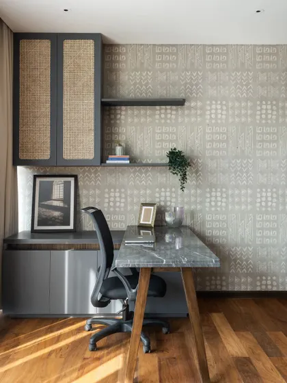 We designed this home office to be a space of quiet focus. A custom marble-topped desk is paired with cane-fronted cabinetry and a subtly patterned wallpaper. The interplay of natural wood floors, stone, and woven textures creates a tactile and inspiring work environment.