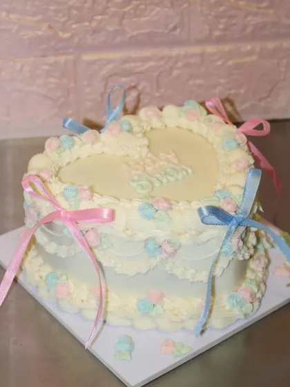 A side view of the heart-shaped baby shower cake, showing the layered design and pastel rosette details.