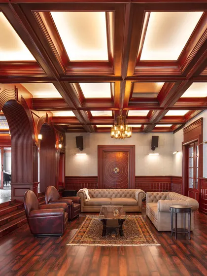 This entertainment lounge in the Wanderlust Villa is inspired by a classic gentleman's club, with rich wood paneling, a coffered ceiling, and comfortable leather seating. It's a moody and atmospheric space perfect for unwinding.