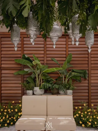 A closer view of the minimalist mandap, showing the simple seating and the beauty of the hanging lanterns and surrounding greenery.