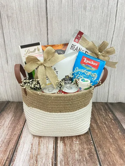 A classic welcome hamper in a jute and cotton basket, filled with snacks and drinks, perfect for any occasion.