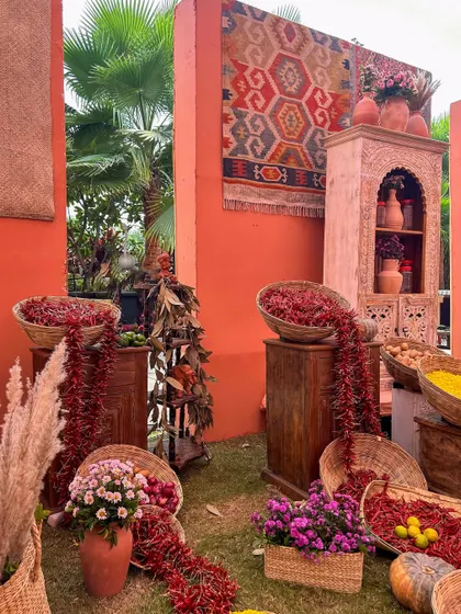 A corner of the bazaar, where baskets overflow with red chilies and spices, set against terracotta walls and a hanging kilim rug. Every detail is curated for authenticity.
