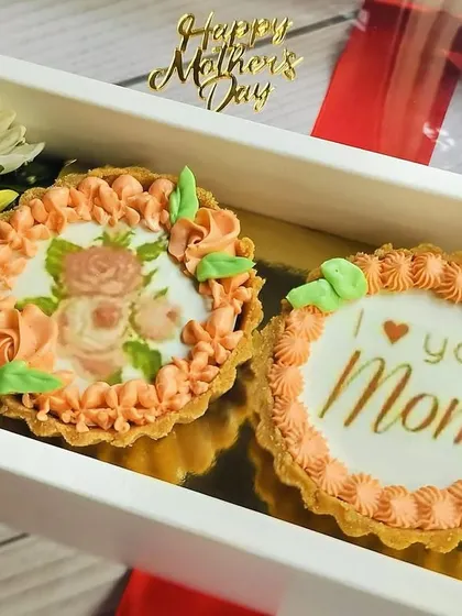 A close-up of the Chocolate Mini Tart Hamper, revealing the detailed edible prints on each tart, one with a floral design and the other with an "I love you Mom" message.