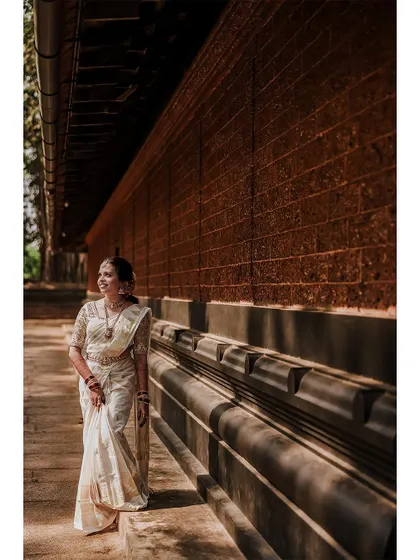 A full-length portrait of the bride against a traditional brick wall.