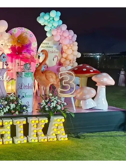 A nighttime view of the flamingo party stage. The marquee letters spelling out 'Lishika' and the themed props create a magical glow.