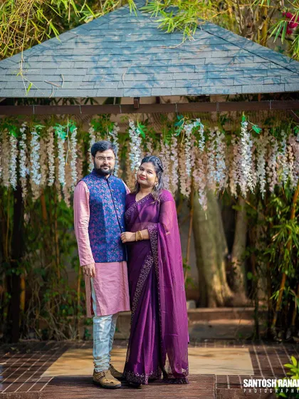 A lovely portrait of a couple in traditional attire posing in a gazebo with hanging wisteria.
