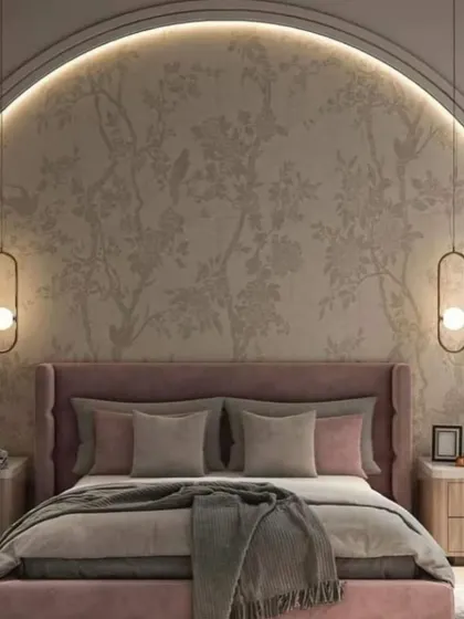A romantic and elegant bedroom featuring a large arched niche with delicate floral wallpaper. The dusty rose upholstered bed and hanging bedside lights complete the soft and sophisticated look.