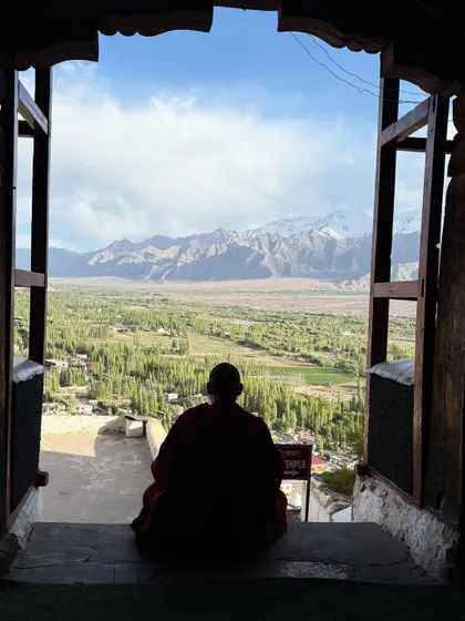 A monk sits in quiet contemplation, looking out from a monastery window at the vast Ladakhi landscape. Moments like these are the heart of our retreats, reminding us to find stillness and connect with our inner world.