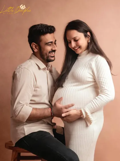 The smiles on their faces say it all. This is a beautiful, candid-style moment from a simple and elegant studio maternity session.