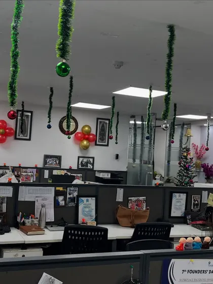 Simple Christmas decorations in an office cubicle area, with hanging green garlands and festive baubles.
