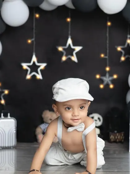 A cute crawling pose from our little man in his all-white outfit, contrasting beautifully with the dark backdrop.