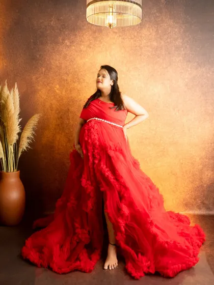 A full-length portrait in a dramatic red ruffled gown. The studio lighting is set to highlight the texture of the dress and create a powerful silhouette.