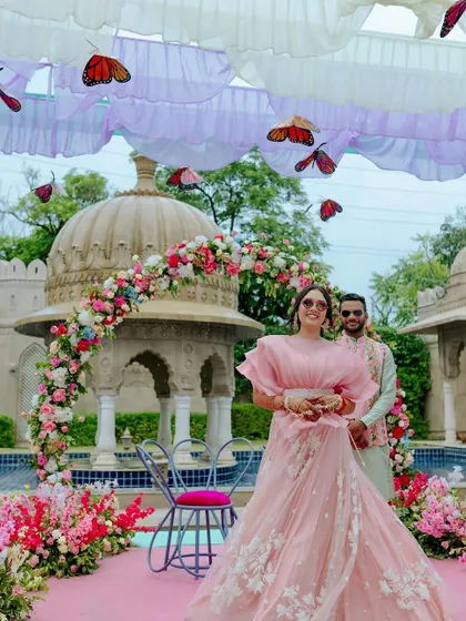 The bride shines at her whimsical Mehendi, with fluttering butterflies suspended from the ceiling and a backdrop of historic architecture.