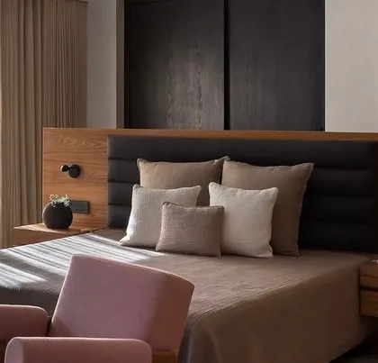 Sunlight streams into this bedroom at the Mango Orchard House, highlighting the natural textures of the bedding and the warm tones of the custom wood headboard.