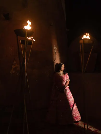 An atmospheric bridal portrait, with the bride illuminated by the warm glow of torches. This creative use of lighting creates a dramatic, almost painterly effect.