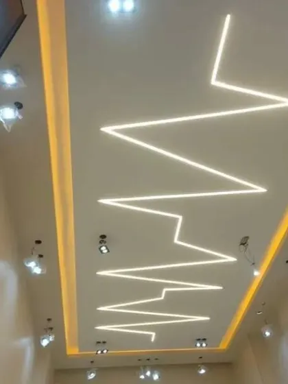 This design uses profile lighting to create a dramatic zigzag or heartbeat pattern across the ceiling. It's a bold and artistic statement for any modern space.