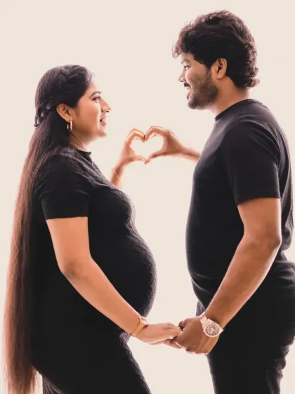 A sweet and simple gesture of love. The father-to-be makes a heart shape with his hands over the baby bump, perfectly capturing the excitement of becoming parents.