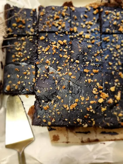 A freshly baked tray of our fudgy chocolate brownies, topped with crunchy nuts. We cut them into generous squares, perfect for grabbing one on the go or adding to a dessert platter.