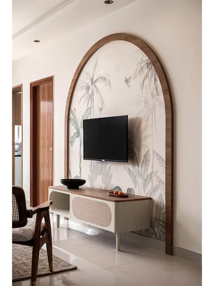 This TV unit in 'The Boho Escape' is framed by a large wooden arch over tropical wallpaper. The design creates a stunning focal point that is both artistic and functional.