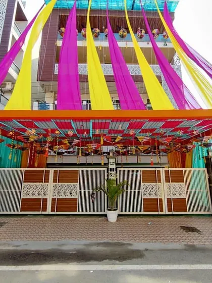 For traditional ceremonies, we create grand entrances. This setup features a full pipe pandaal structure with vibrant yellow, pink, and orange fabric draping and decorative hangings to welcome guests.