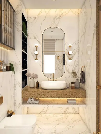 A bright and elegant bathroom with white marble walls and gold accents. The design features a floating vanity, an oval mirror with sconces, and a fluted glass storage cabinet.