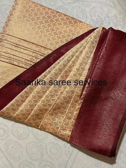 A beige saree with a maroon border, neatly box-folded. This shows the final product that is easy to store.