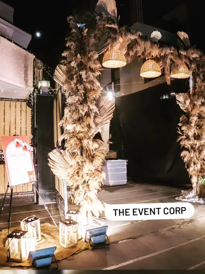 The entrance to an intimate baby shower, featuring a rustic-chic arch made of pampas grass and lit by lanterns.