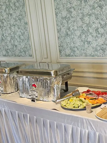 A clean and professional buffet setup, with chafing dishes and a fresh salad platter ready for guests.