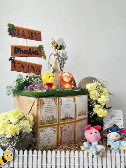 A journey into the Hundred Acre Wood to welcome the Bhatia twins. This charming Winnie the Pooh hamper is filled with character plushies, storybook quotes, and sweet treats, all nestled in a rustic, garden-like setting.
