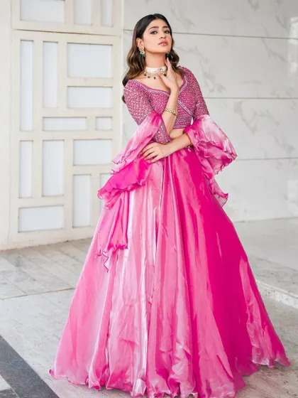 A full-length view of the rose pink lehenga with its unique tiered skirt and dramatic sleeves. This outfit is designed to make a statement and is perfect for dancing the night away.