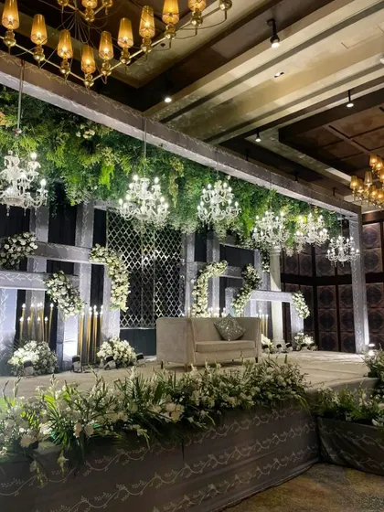 A closer view of the white and green reception stage, highlighting the intricate details of the floral arrangements and the elegant seating.