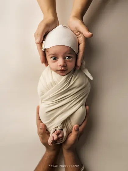 A perfectly swaddled newborn held between their parents' hands. This "in your hands" pose is a beautiful way to show the scale of your tiny baby and the safety of your embrace.