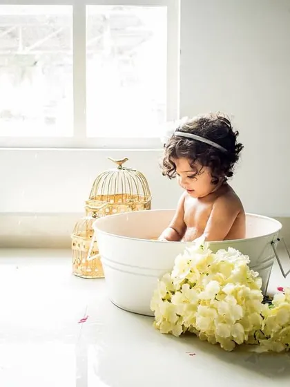 A beautiful, minimalist milk bath session. The simple white tub and flowers create an artistic and serene portrait of this little "Goldilocks."