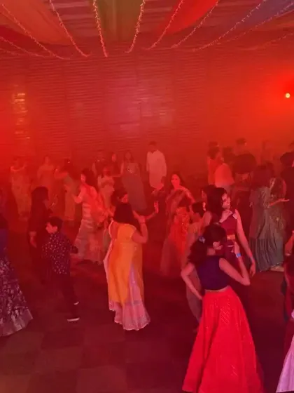 The dance floor filled with guests in colorful traditional wear, dancing under the warm red lights.