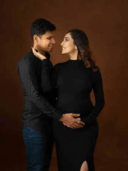 The quiet moments between a couple are just as important. This intimate portrait showcases their bond, with elegant, coordinated black outfits against a rich brown backdrop for a timeless feel.