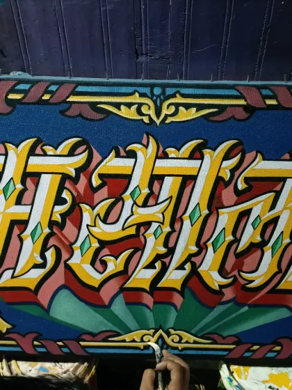 A work-in-progress shot of a complex lettering piece, showing the layering of colors to create a metallic, three-dimensional effect.
