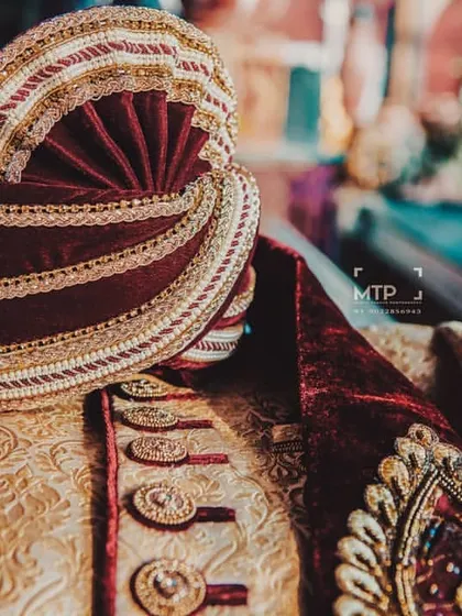 A close-up of the groom's pagdi (turban) and the collar of his sherwani, showcasing the rich velvet and gold trim.