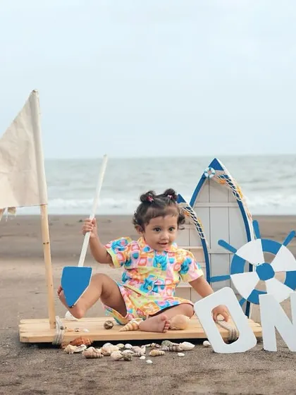 A close-up of a little girl playing with a shovel and shells during her nautical-themed beach photoshoot.