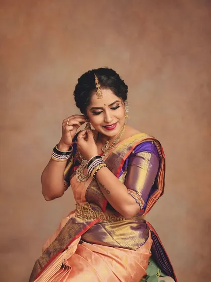 A candid-style shot of her adjusting an earring adds a touch of life and personality. It highlights the traditional jhumkas and the elegant hairstyle, completing the festive look.