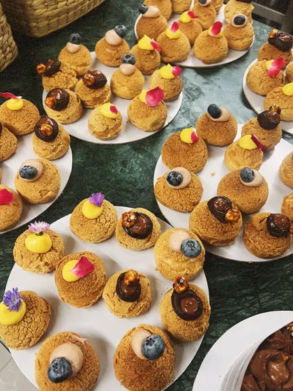 Plates of assorted choux pastries, decorated with fresh blueberries and edible flower petals. These were for a Rakshabandhan order, and I'm forever grateful to be part of your celebrations.