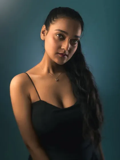 A classic studio portrait with soft lighting against a textured blue backdrop. The focus here is on creating a clean, timeless look that highlights the subject's expression.