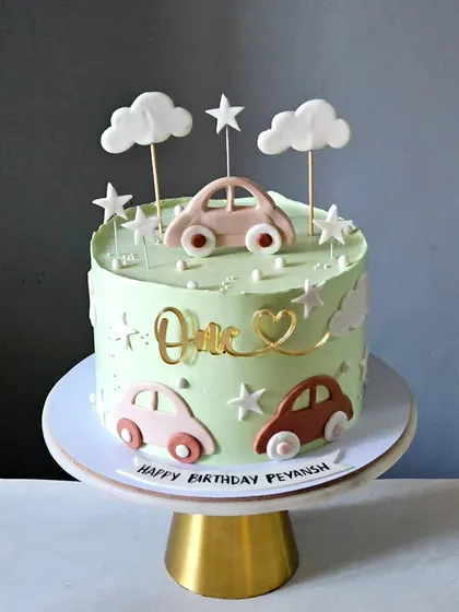 A first birthday cake with a unique color palette. This car-themed cake uses pastel green and earthy brown tones for a standout, modern look.