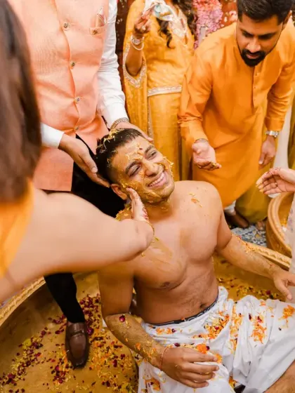 The groom, stripped of his kurta, gets ready for the messy part of the haldi. This shot captures the anticipation and fun of the boys' side of the celebration.